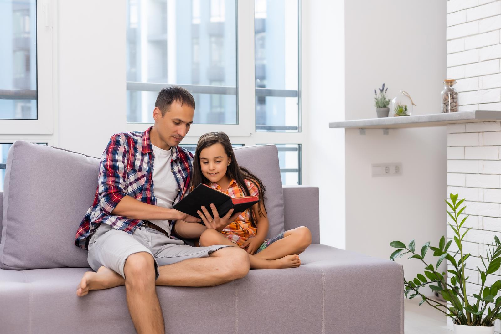 Father reading Bible to his little child daughter at home